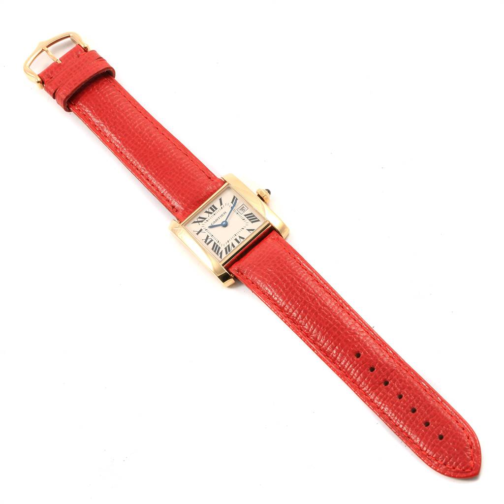 The Cartier Tank Française watch is shown from a top-down angle, displaying its face, case, and red leather strap.