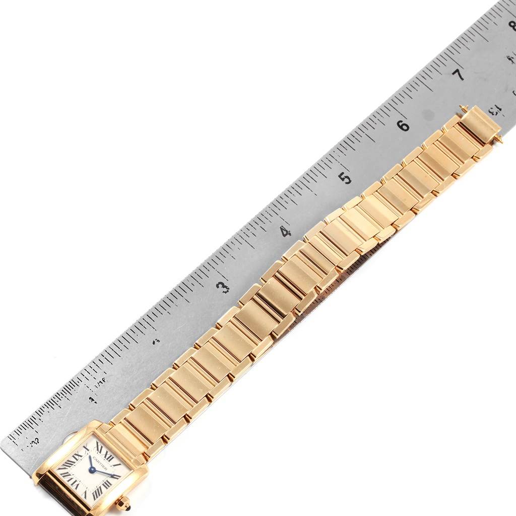This image shows a side view of a gold Cartier Tank Francaise W50002N2 Women's Yellow Gold Silver Dial W50002N2 Women's Yellow Gold Silver Dial watch next to a ruler, highlighting the band and face.
