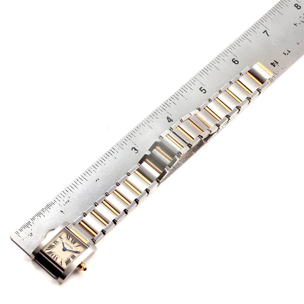This image shows the Cartier Tank Francaise W51007Q4 Women's Steel and Gold (two tone) Silver Dial W51007Q4 Women's Steel and Gold (two tone) Silver Dial watch laying flat next to a ruler, displaying its face and bracelet.