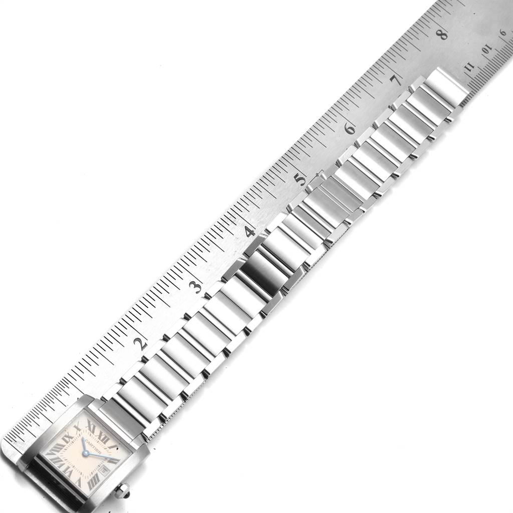 The image shows a Cartier Tank Francaise W51011Q3 Women's Stainless Steel Silver Dial W51011Q3 Women's Stainless Steel Silver Dial watch placed next to a ruler, highlighting the metal bracelet and part of the watch face.