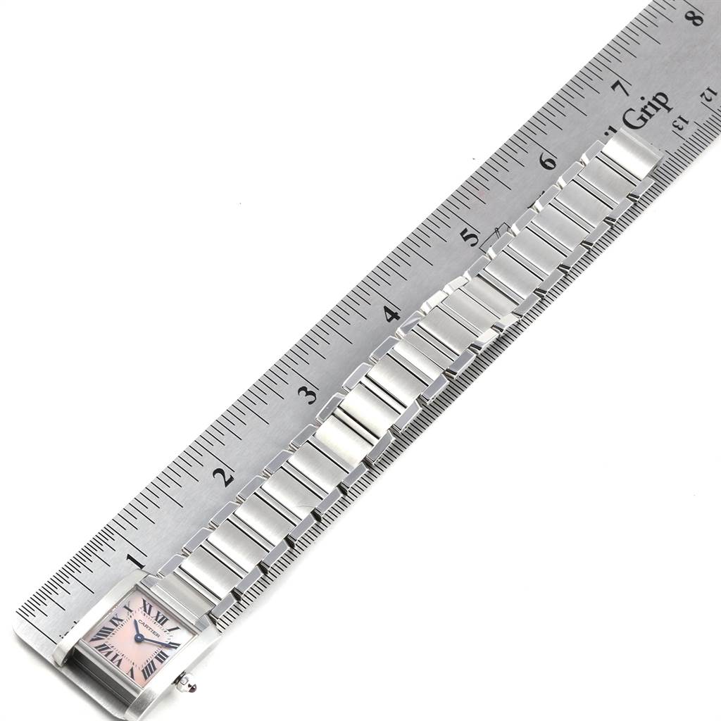 The image shows a top-down view of a Cartier Tank Française watch, highlighting its metal bracelet and rectangular face alongside a ruler.