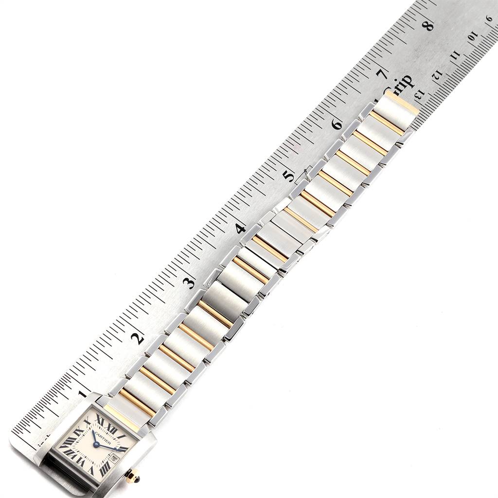 The image shows a Cartier Tank Francaise W51012Q4 Women's Steel and Gold (two tone) Silver Dial W51012Q4 Women's Steel and Gold (two tone) Silver Dial watch laid flat next to a ruler, highlighting its face and bracelet.