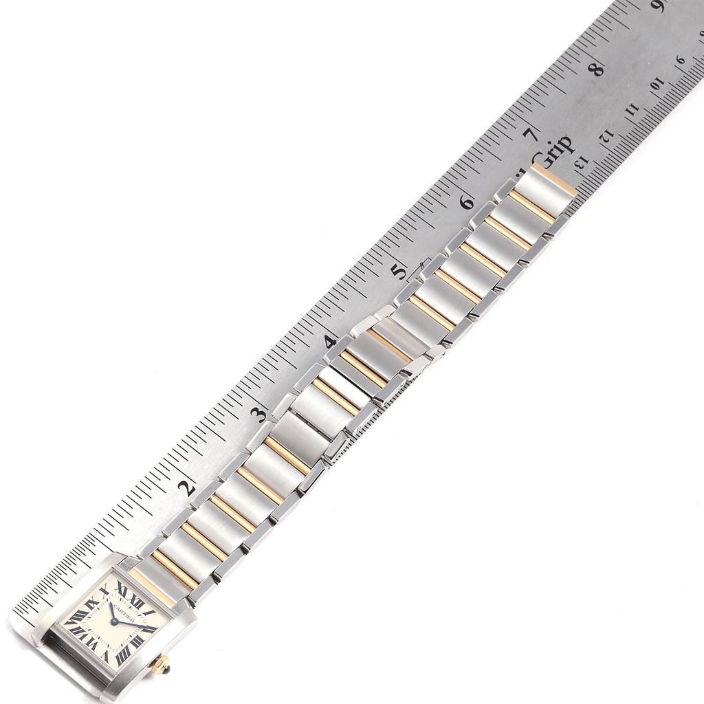 The Tank Francaise model by Cartier is shown from an overhead angle, displaying its face and bracelet next to a ruler.