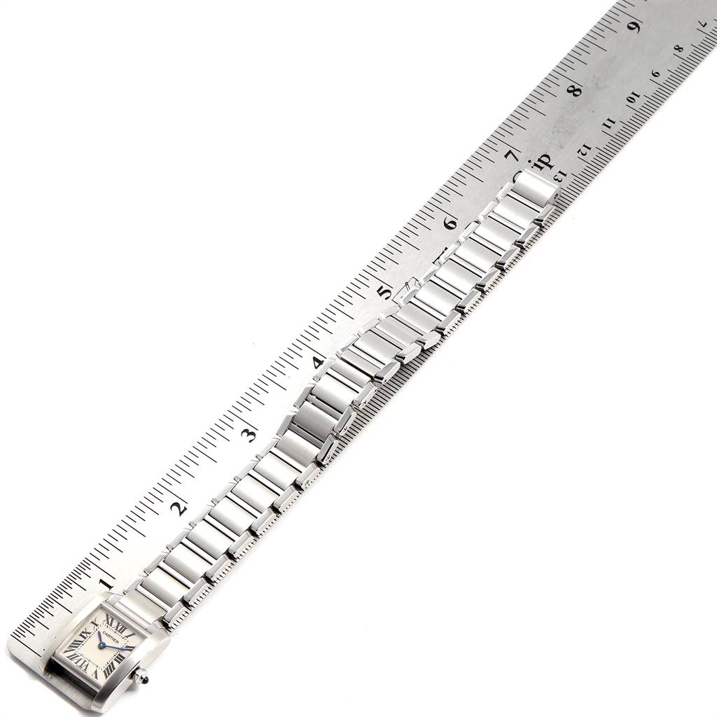 The Cartier Tank Francaise W51008Q3 Women's Stainless Steel Silver Dial W51008Q3 Women's Stainless Steel Silver Dial watch is placed next to a ruler, displaying its square face and metal bracelet.