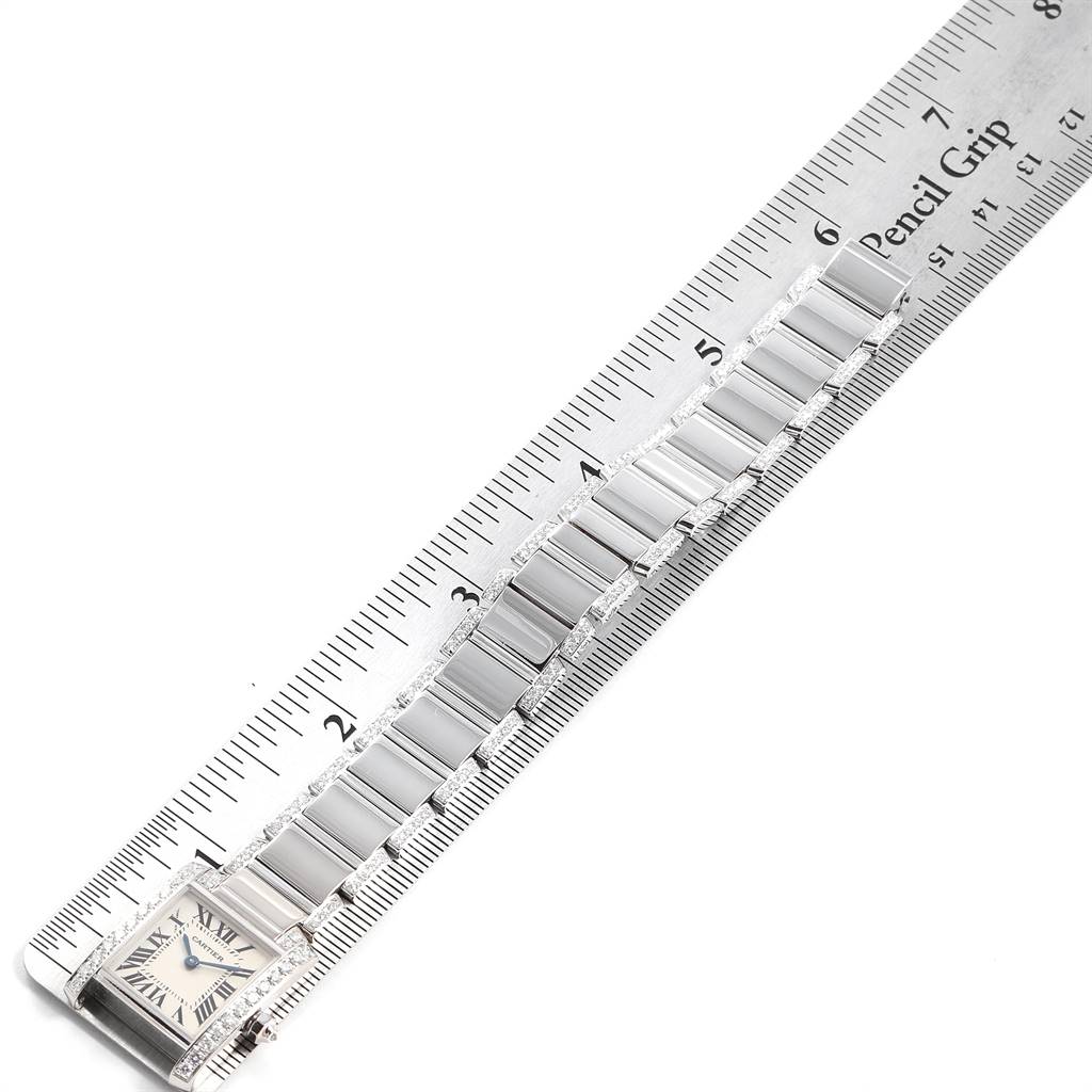 The image shows a Cartier Tank Francaise WE1002SF Women
s White Gold Silver Dial WE1002SF Women
s White Gold Silver Dial watch at an angle, focusing on its face and stainless steel bracelet alongside a ruler.