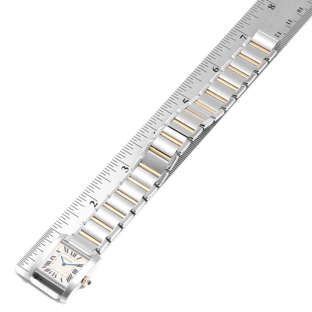 This image shows the face and bracelet of a Cartier Tank Française watch, measured against a ruler.