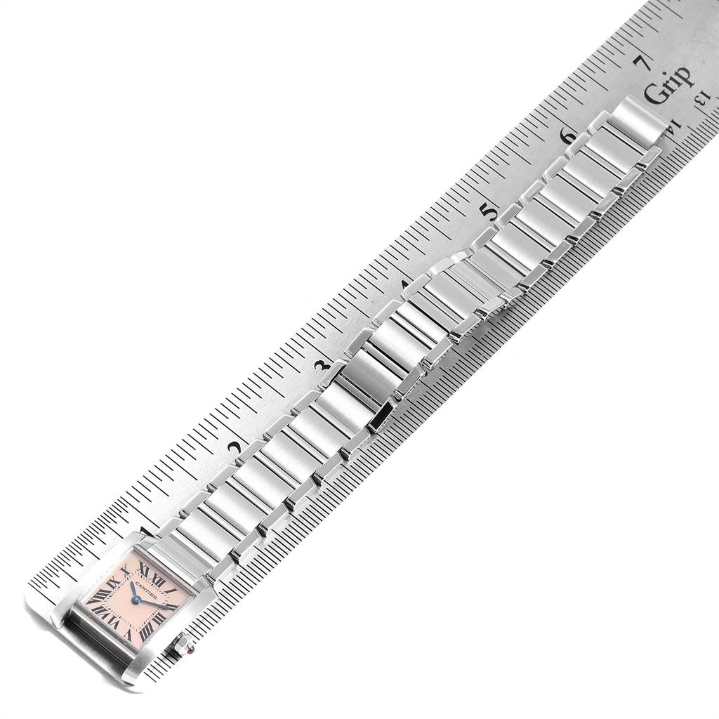 The image shows a Cartier Tank Française watch laid flat against a ruler, highlighting the watch's face and bracelet in a top-down view.