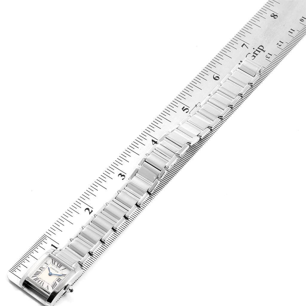 The image shows a top-down view of a Cartier Tank Francaise W50012S3 Women's White Gold Silver Dial W50012S3 Women's White Gold Silver Dial watch next to a ruler, focusing on the entire watch and its metal bracelet.