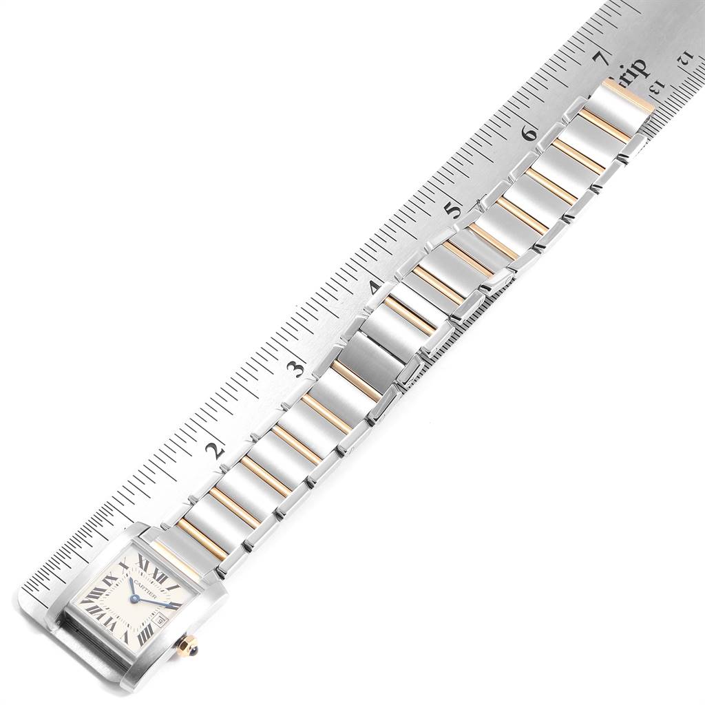 The image shows the front view of a Cartier Tank Francaise W51012Q4 Women's Steel and Gold (two tone) Silver Dial W51012Q4 Women's Steel and Gold (two tone) Silver Dial watch and its entire metal bracelet laid alongside a ruler for measurement.