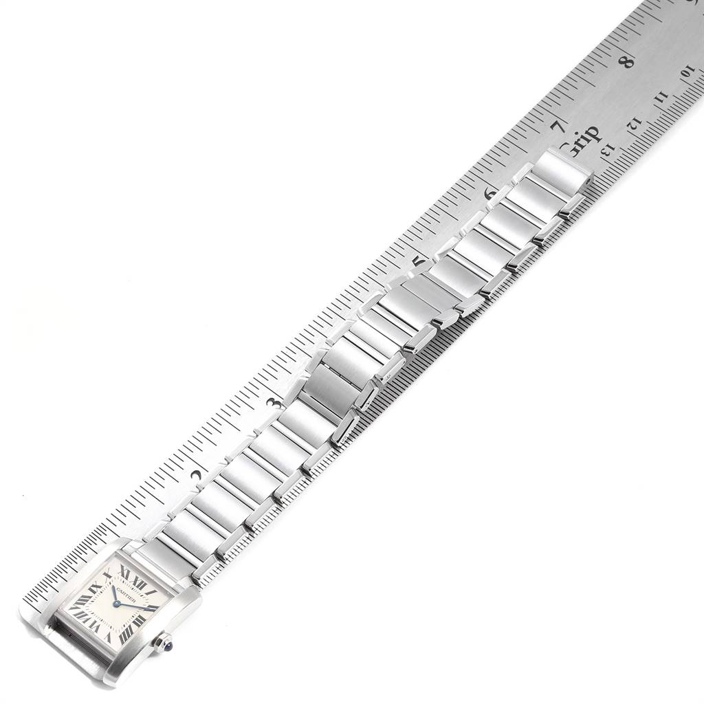 The Cartier Tank Française watch is shown in a top-down view with the face and bracelet laid out next to a ruler.