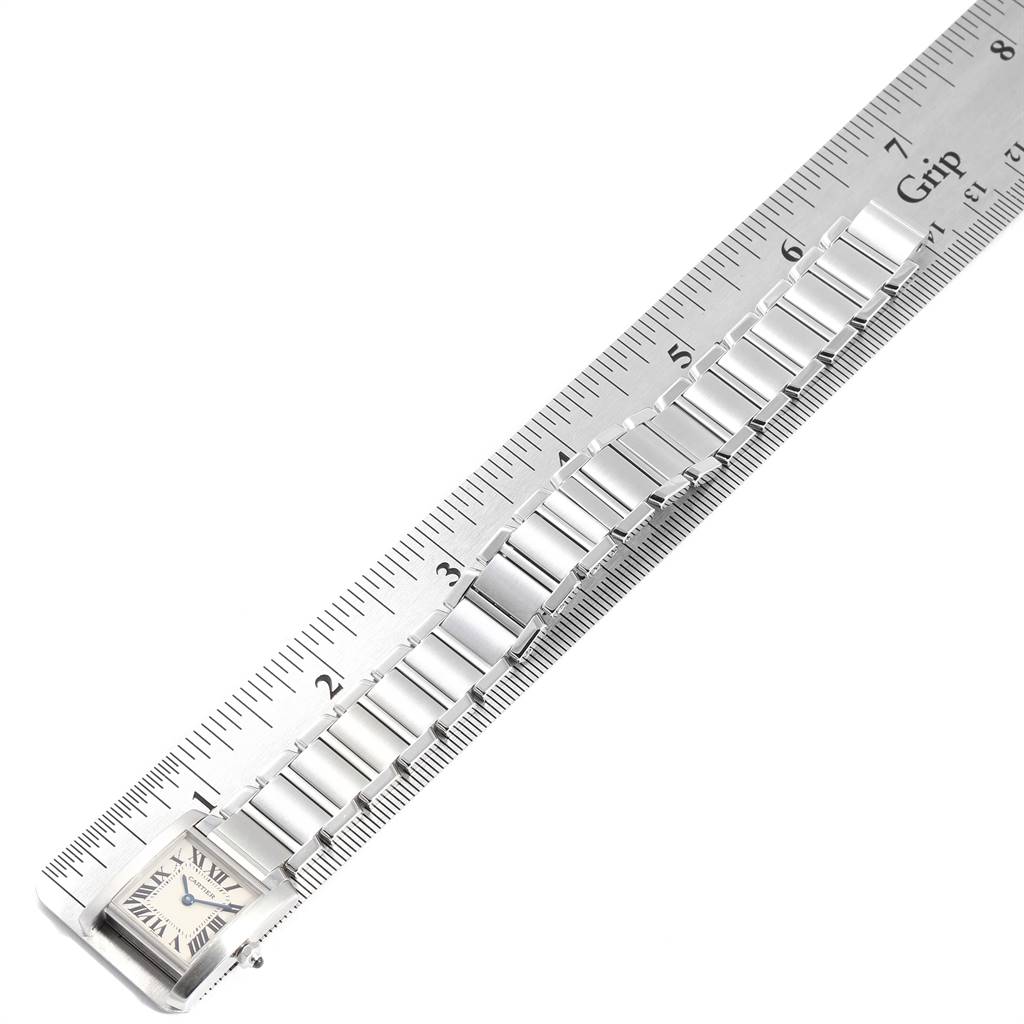 The image shows a Tank Francaise watch by Cartier with its bracelet aligned along a ruler, displaying a top-down view.