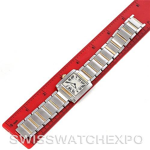 The image shows a top view of a Cartier Tank Française watch, laid against a red ruler for scale.