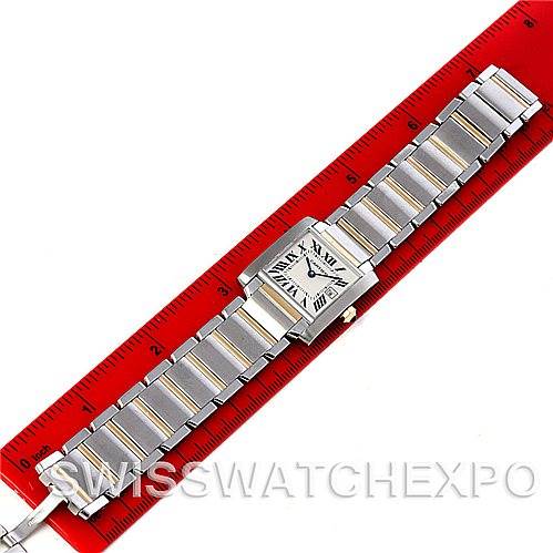 The image shows a top-down view of a Cartier Tank Française watch laid flat against a red ruler.