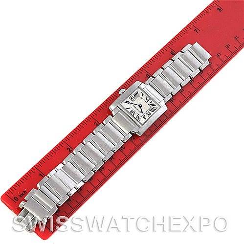 This image shows the Cartier Tank Française watch laid flat against a red ruler, showcasing its bracelet and square face from a top-down angle.