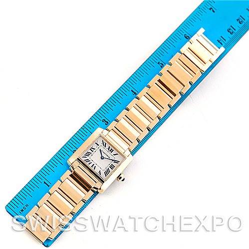 The image shows a Cartier Tank Francaise W50003N2 Women's Yellow Gold Silver Dial W50003N2 Women's Yellow Gold Silver Dial watch laid flat next to a blue ruler, highlighting its bracelet and rectangular face.