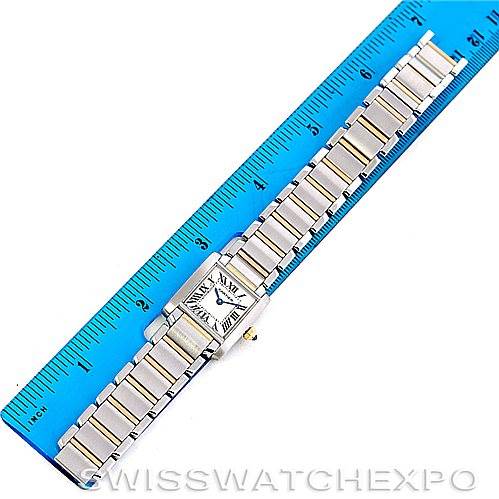 The Cartier Tank Française watch is shown from a top view, displaying its band against a blue ruler backdrop.