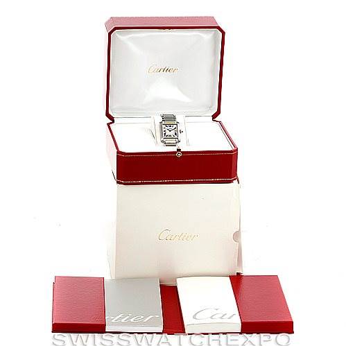 This image shows a Tank Francaise watch by Cartier placed in an open red box with additional accessories and booklets displayed below.