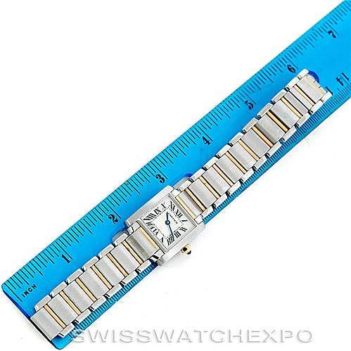 The image shows a Cartier Tank Française watch laid flat next to a blue ruler for scale, displaying its face and metal bracelet.