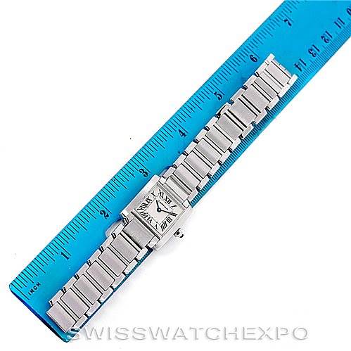 This image shows a Cartier Tank Française watch laid flat next to a blue ruler measuring its length.