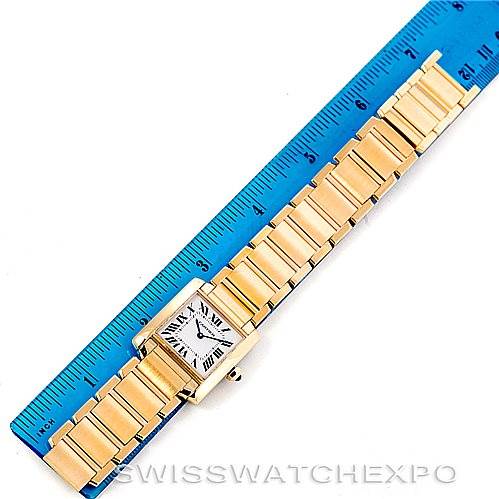 The image shows a Cartier Tank Française watch laid flat next to a blue ruler for size reference.