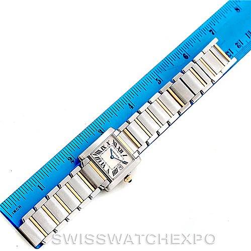 The Cartier Tank Française watch is shown from a top-down angle, with its face, bezel, bracelet, and crown visible, next to a ruler.