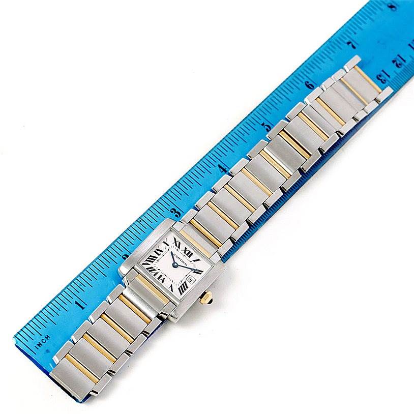 The image shows a Tank Francaise by Cartier watch lying flat next to a ruler for scale.