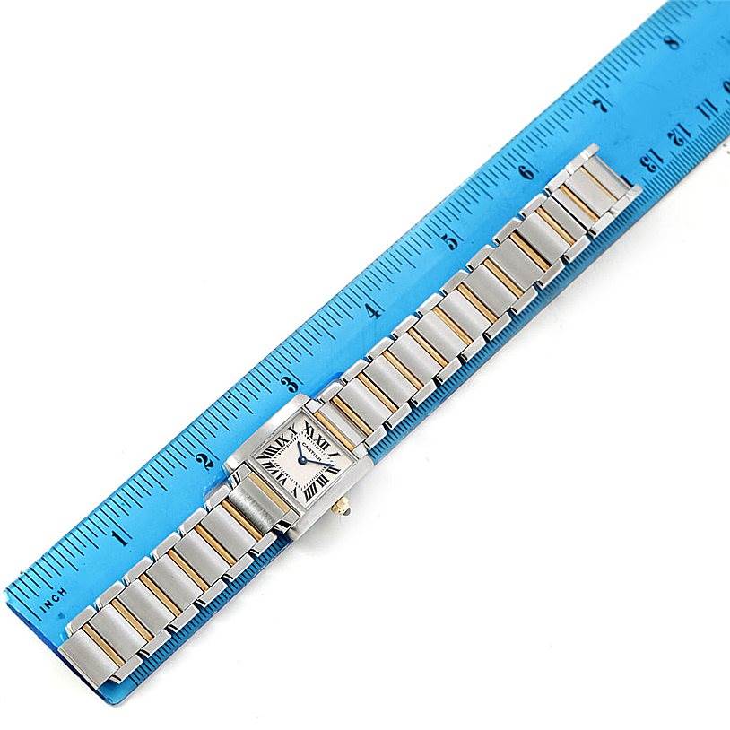 The image shows a top view of a Cartier Tank Francaise W51007Q4 Women's Steel and Gold (two tone) Silver Dial W51007Q4 Women's Steel and Gold (two tone) Silver Dial watch with its metal bracelet placed next to a blue ruler for scale.