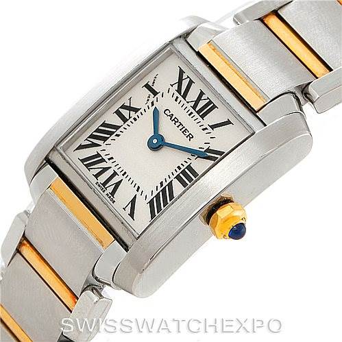 The image shows a Cartier Tank Francaise W51007Q4 Women's Steel and Gold (two tone) Silver Dial W51007Q4 Women's Steel and Gold (two tone) Silver Dial watch viewed at an angle highlighting its rectangular dial, Roman numerals, two-tone band, and blue cabochon crown.