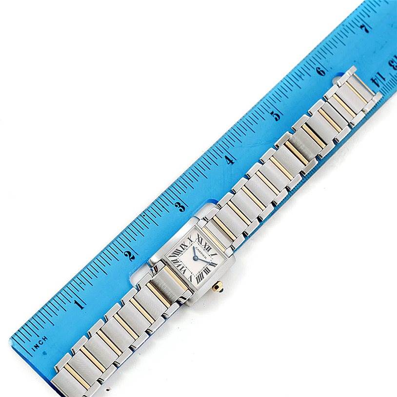 The image shows a Cartier Tank Française watch laid flat with a blue ruler for scale.