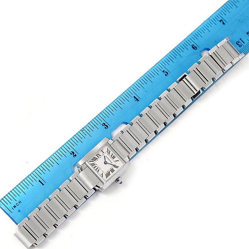 The image shows the Cartier Tank Francaise W51008Q3 Women's Stainless Steel Silver Dial W51008Q3 Women's Stainless Steel Silver Dial watch placed next to a blue ruler, highlighting its full bracelet and rectangular face.