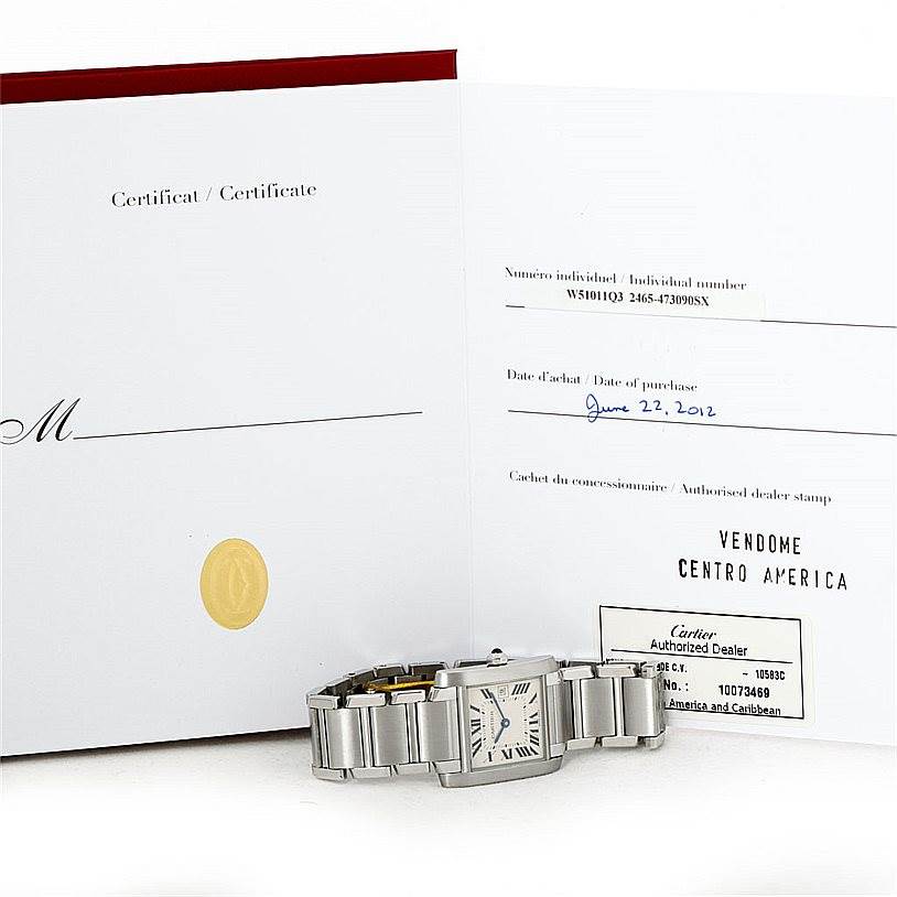 The image shows a Cartier Tank Française watch placed in front of its open certificate and authorized dealer documentation.