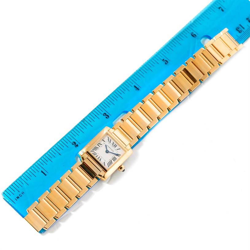 The image shows a Cartier Tank Francaise W50002N2 Women's Yellow Gold Silver Dial W50002N2 Women's Yellow Gold Silver Dial watch laid next to a blue ruler, viewed from above, displaying the bracelet and face.