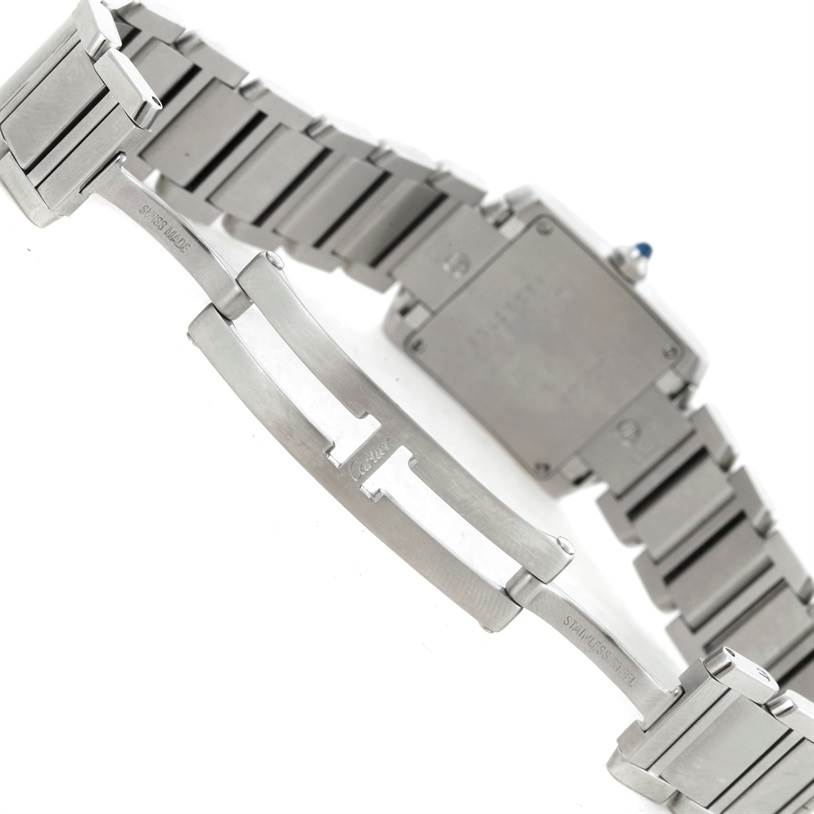 The image shows the underside of a Cartier Tank Française watch, focusing on the bracelet, clasp, and case back.