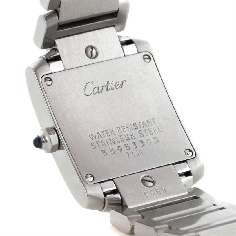 The image shows the back case and part of the bracelet of a Tank Française by Cartier at an angle, emphasizing its engravings.
