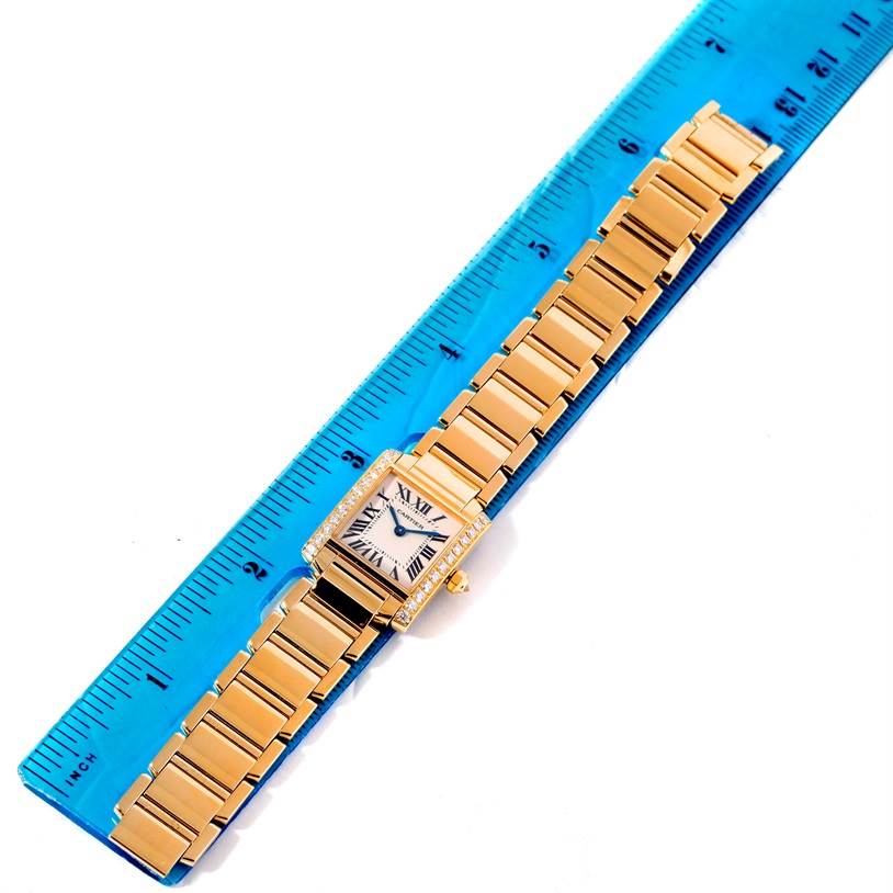 The image shows a top view of the Cartier Tank Francaise WE1001R8 Women's Yellow Gold Silver Dial WE1001R8 Women's Yellow Gold Silver Dial watch, displaying its face and full bracelet on a ruler.