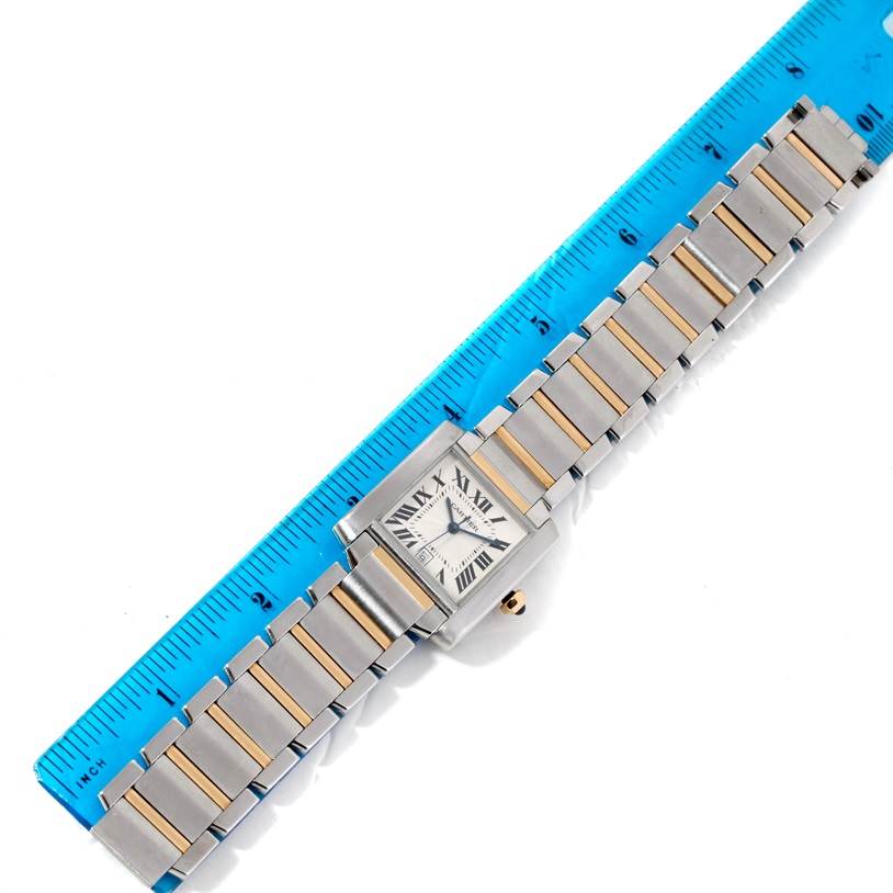 The image shows an overhead view of a Cartier Tank Francaise W51005Q4 Steel and Gold (two tone) Silver Dial W51005Q4 Steel and Gold (two tone) Silver Dial watch with a two-tone bracelet, next to a blue ruler for scale.