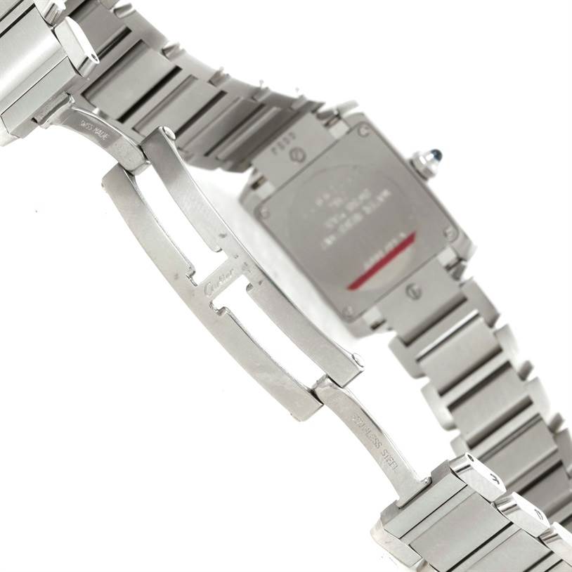 The image shows the underside of a Cartier Tank Française watch, highlighting its stainless steel bracelet and clasp mechanism.
