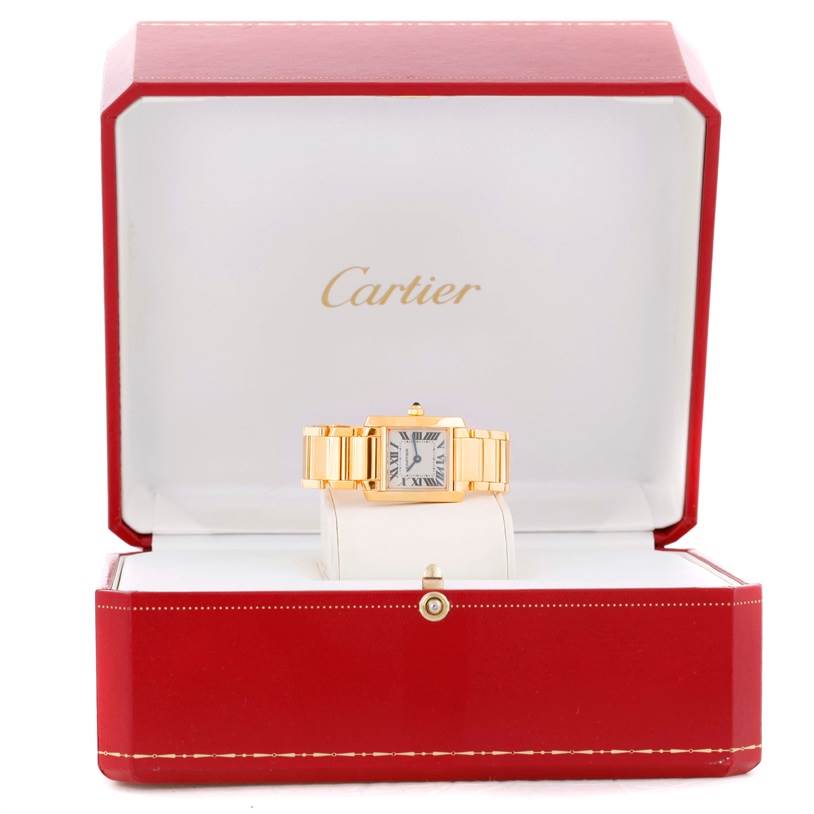 The Cartier Tank Française watch is shown front-facing in an open red box with a gold-tone band and white dial.