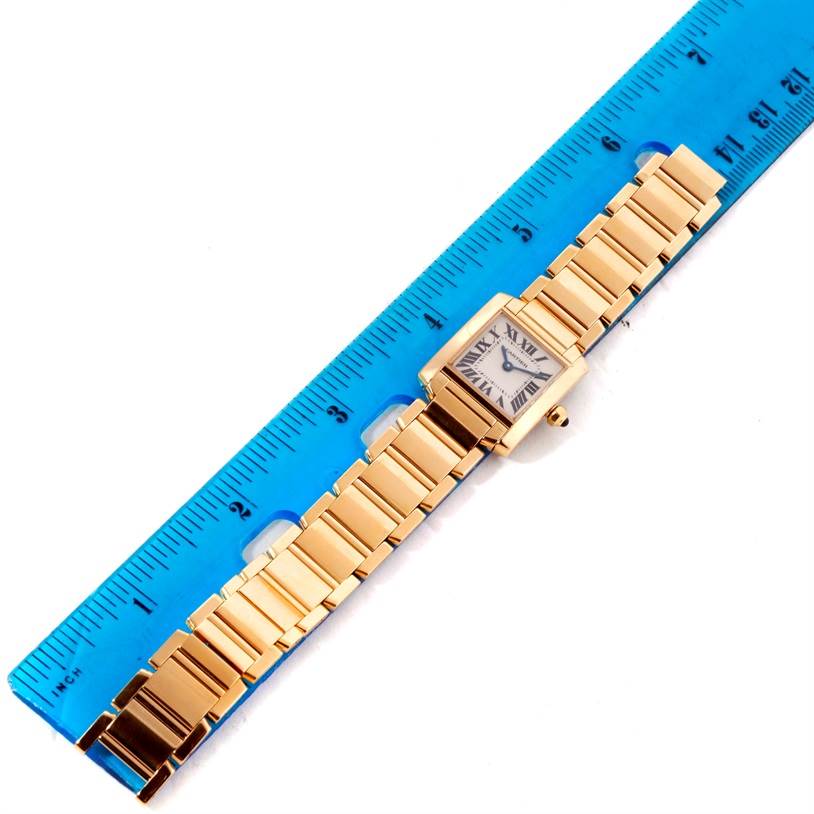 The Cartier Tank Francaise W50002N2 Women's Yellow Gold Silver Dial W50002N2 Women's Yellow Gold Silver Dial watch is shown from a top-down angle next to a blue ruler, highlighting its face and bracelet.