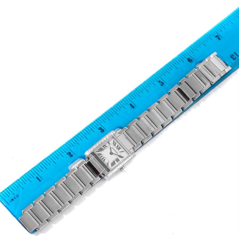 The image shows a Tank Française model by Cartier from a top-down angle, displaying the entire watch band and face aligned with a ruler.
