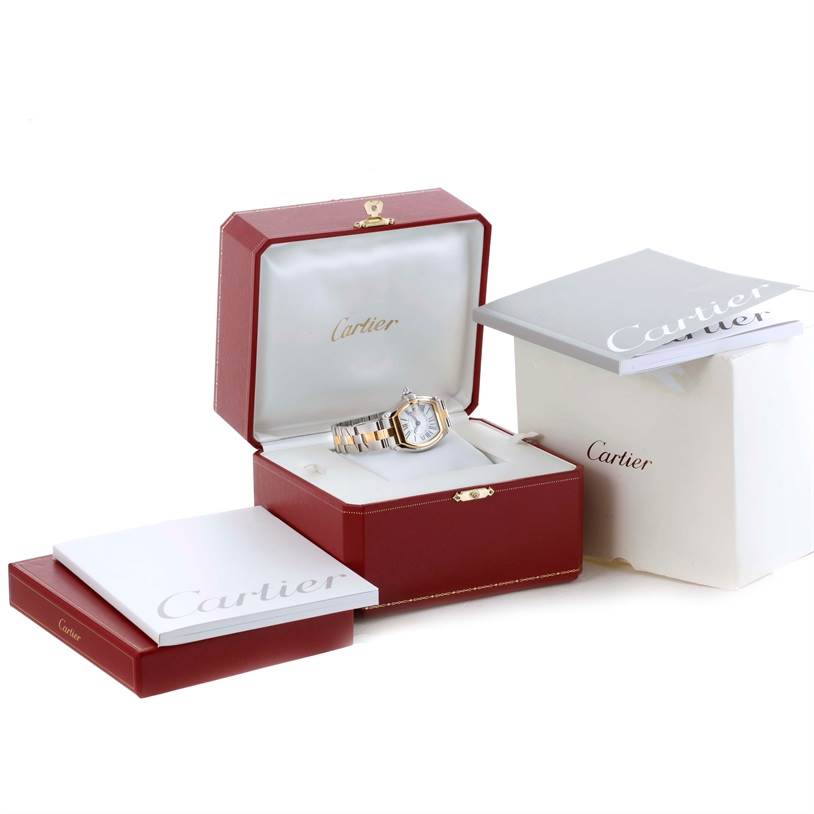 The Cartier Roadster W62026Y4 Women's Steel and Gold (two tone) Silver Dial W62026Y4 Women's Steel and Gold (two tone) Silver Dial watch is shown in its open display box, surrounded by packaging and booklets.