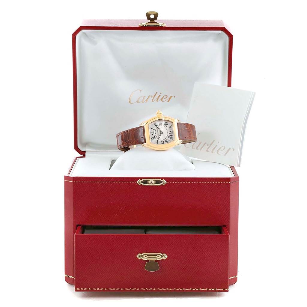 The Cartier Roadster W62018Y5 Women's Yellow Gold Silver Dial W62018Y5 Women's Yellow Gold Silver Dial watch is displayed front-on in its open red box with a brown leather strap and accompanying documents.