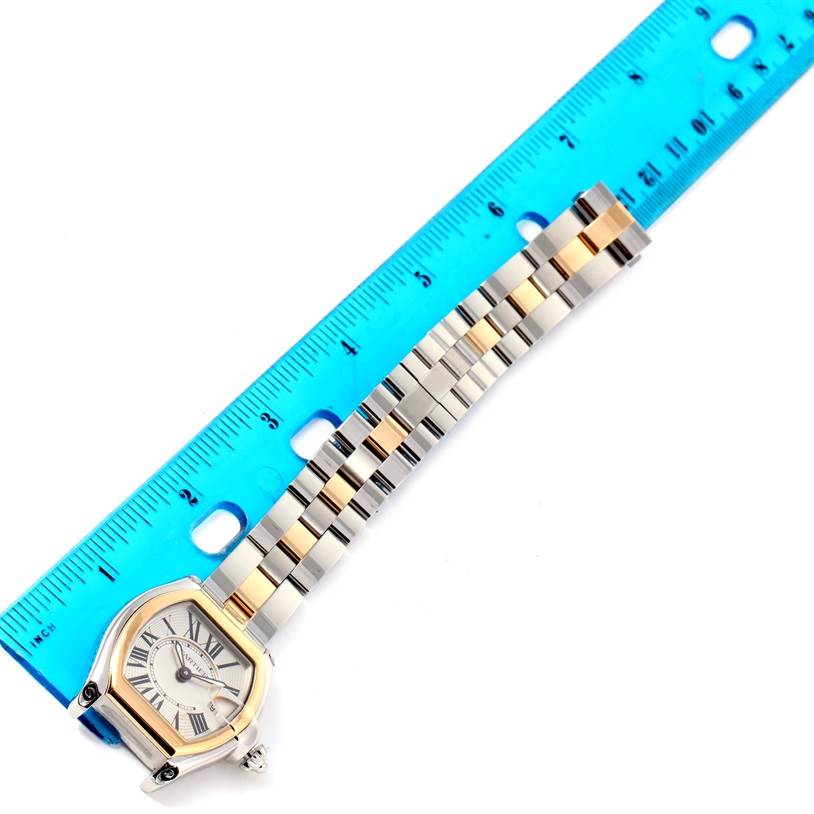 The image shows the Cartier Roadster W62026Y4 Women's Steel and Gold (two tone) Silver Dial W62026Y4 Women's Steel and Gold (two tone) Silver Dial watch laid flat next to a ruler, displaying its face and metal band.