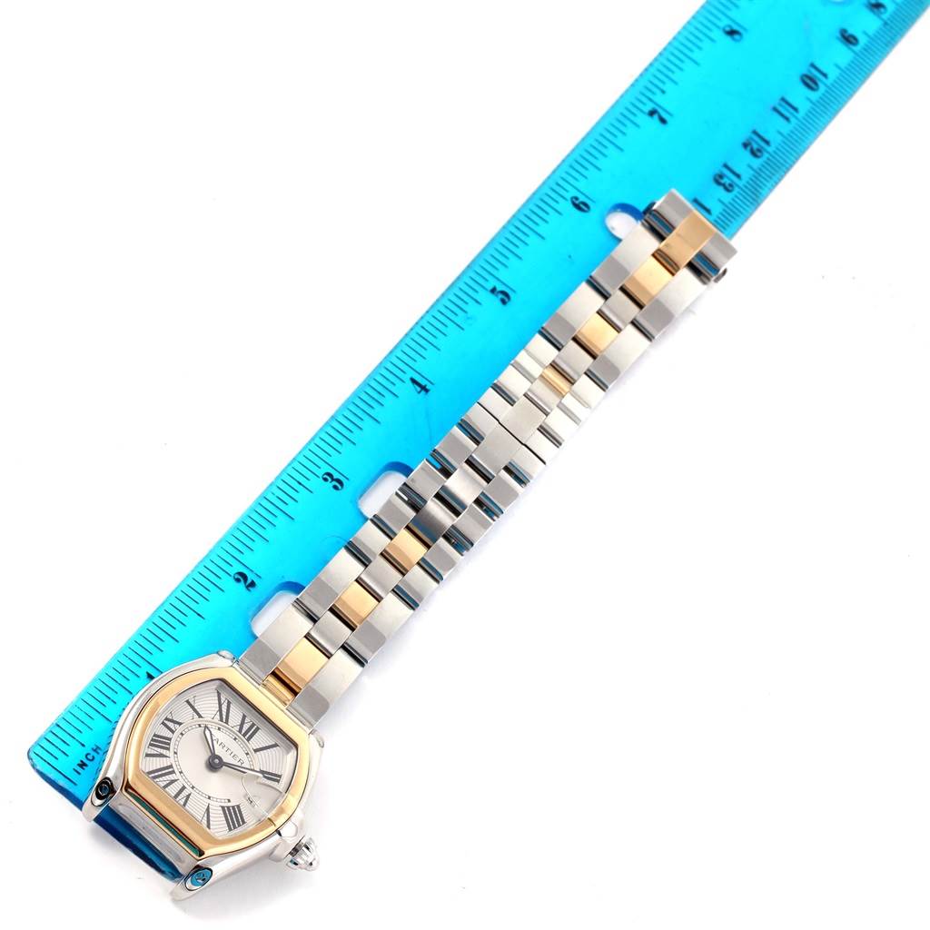 The image shows the Cartier Roadster W62026Y4 Women's Steel and Gold (two tone) Silver Dial W62026Y4 Women's Steel and Gold (two tone) Silver Dial watch with its face and band laid out next to a blue ruler for scale.