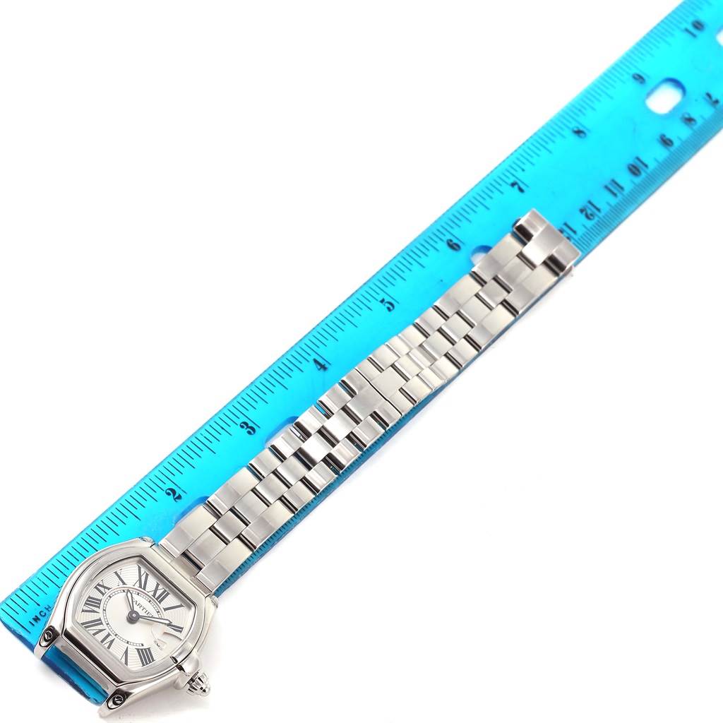 The image shows a top-down view of a Cartier Roadster W62016V3 Women's Stainless Steel Silver Dial W62016V3 Women's Stainless Steel Silver Dial watch with its face, bracelet, and a ruler for scale.