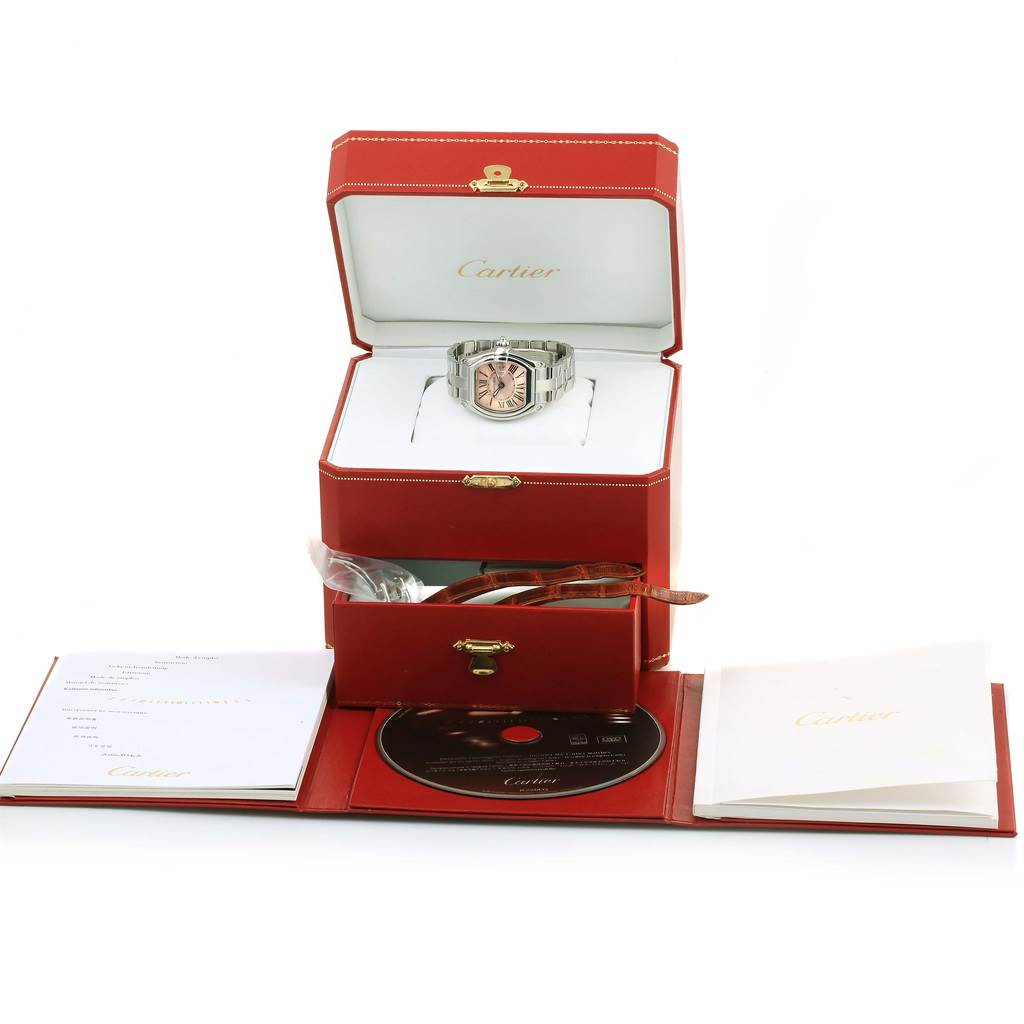 This image shows the Cartier Roadster W62043V3 Women's Stainless Steel Pink Dial W62043V3 Women's Stainless Steel Pink Dial watch in a red box, with paperwork and accessories including a booklet and a CD displayed.
