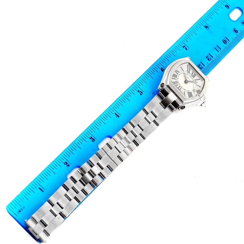 The Cartier Roadster W62016V3 Women's Stainless Steel Silver Dial W62016V3 Women's Stainless Steel Silver Dial watch is shown from a top-down angle alongside a blue ruler, displaying the face and metal bracelet.