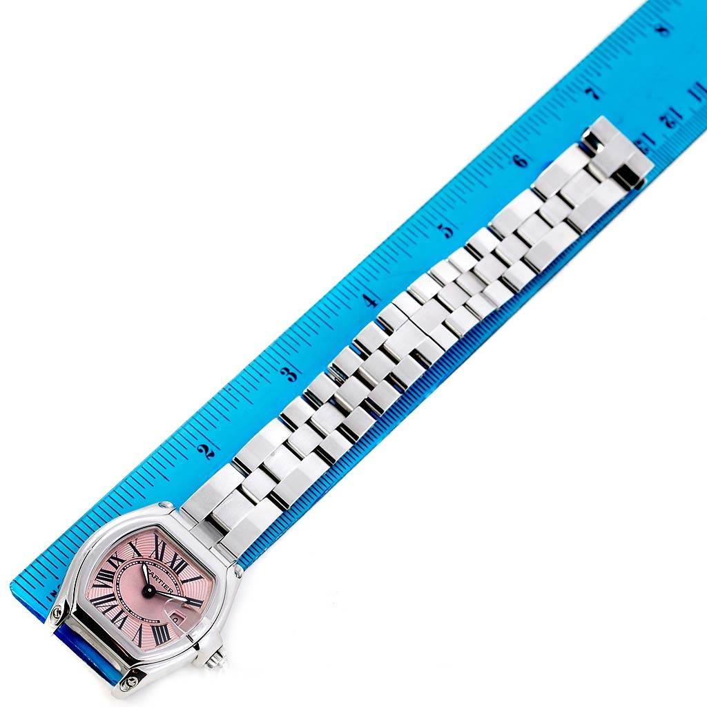 The image shows the Cartier Roadster W62017V3 Women's Stainless Steel Pink Dial W62017V3 Women's Stainless Steel Pink Dial watch laid flat with its bracelet and case next to a blue ruler for scale.