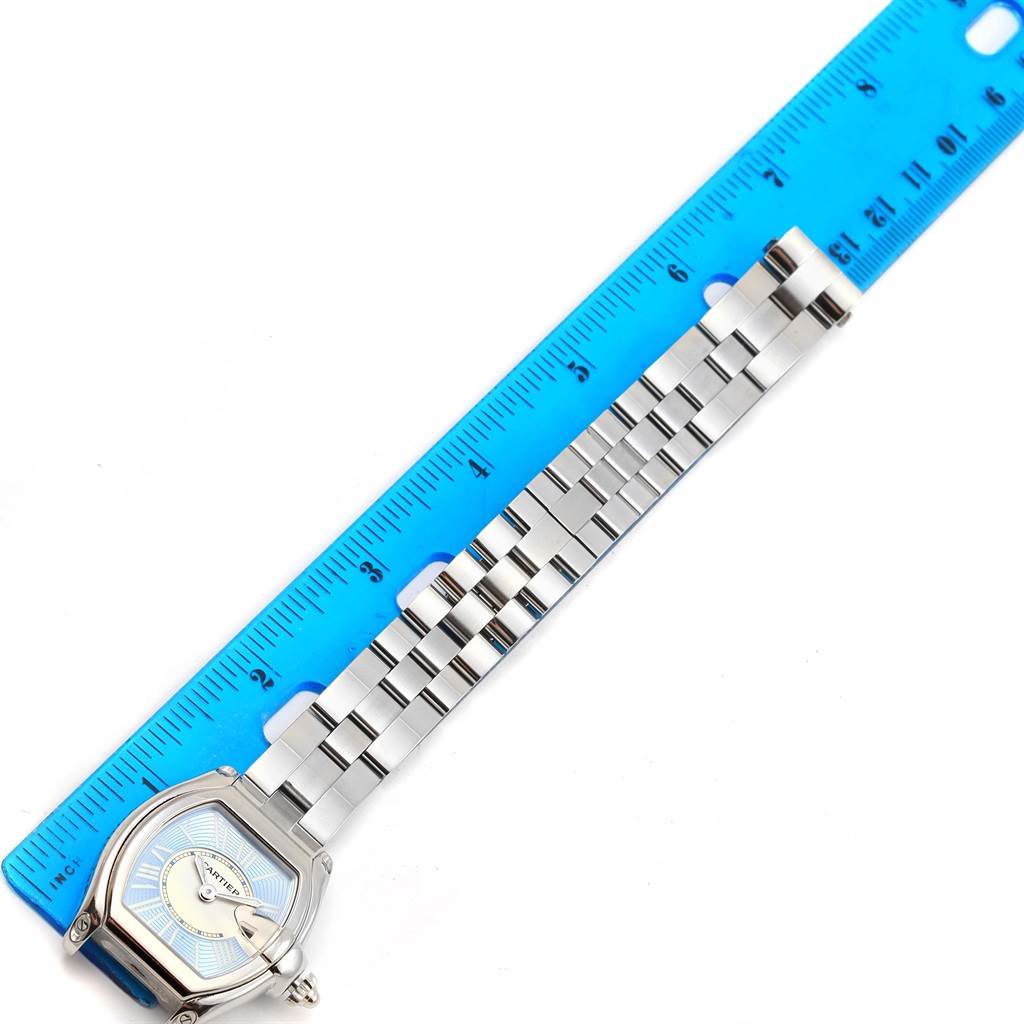 The Cartier Roadster W62053V3 Women's Stainless Steel Blue Dial W62053V3 Women's Stainless Steel Blue Dial watch is shown flat with a blue ruler for size reference, highlighting the face and bracelet.