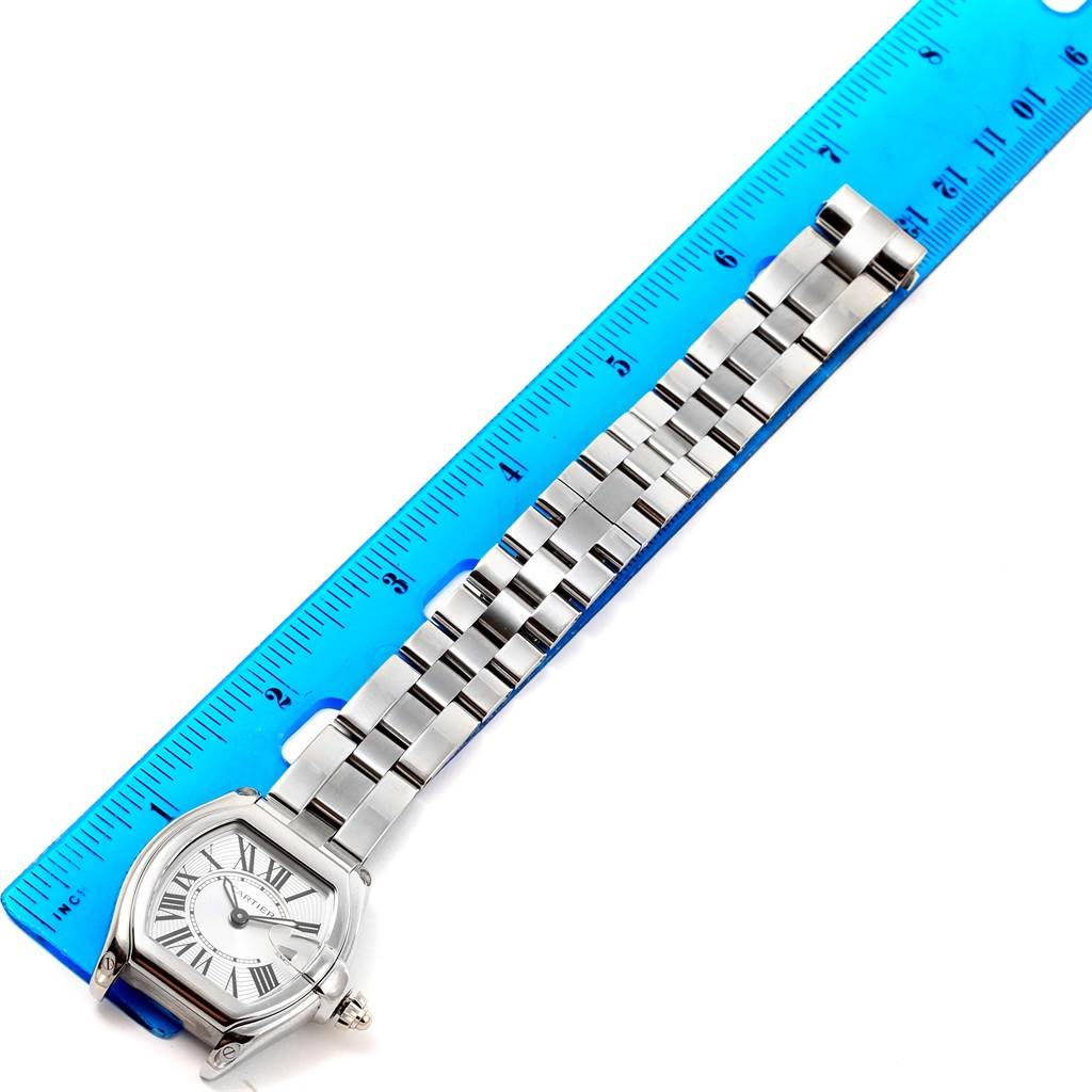 The Cartier Roadster W62016V3 Women
s Stainless Steel Silver Dial W62016V3 Women
s Stainless Steel Silver Dial watch is shown from a top-down angle, displaying its face, band, and part of a blue ruler for scale.